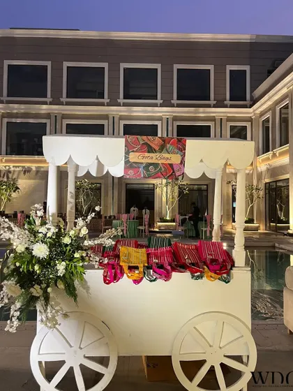 A cute and interactive addition to the celebration. This white cart is filled with colorful bangles for guests, and adorned with fresh flowers, adding a touch of cultural charm.
