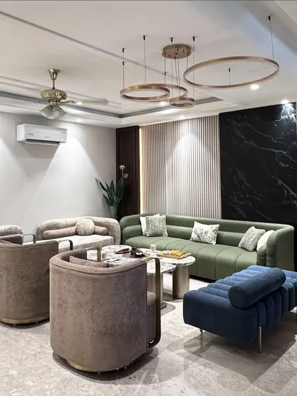 A modern living room featuring a bold color palette. We designed and manufactured the plush green L-shaped sofa, the contrasting blue bench, and the elegant taupe armchairs to create a dynamic yet harmonious space.