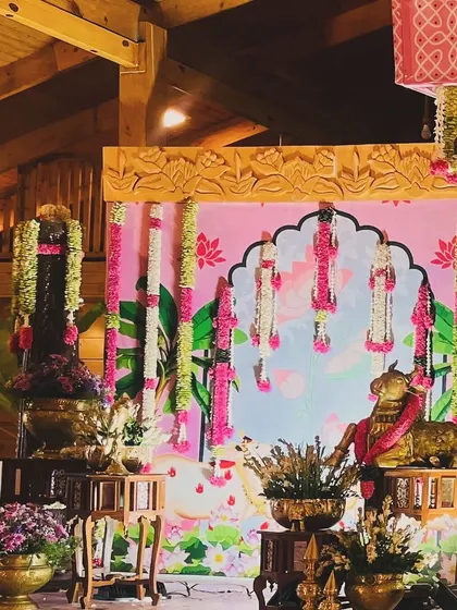 A side view of the naming ceremony stage, showing the depth and detail of the decor. The combination of the wooden structure, pink backdrop, and hanging flowers creates a truly magical setting.