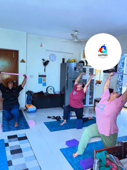A group of women use resistance bands for a warrior pose variation, adding a challenge to build shoulder and back strength while improving flexibility.