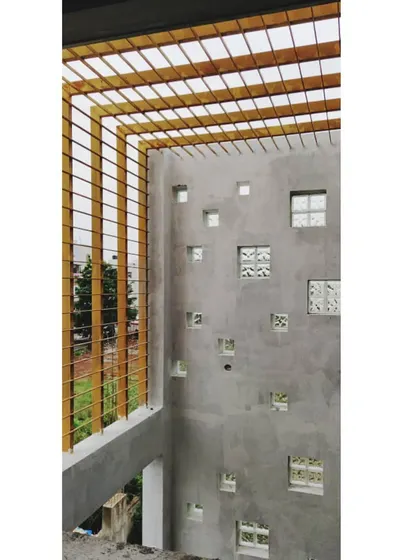 A view of a backyard wall under construction. This design features a pattern of square niches with glass blocks and an overhead MS pergola, which will eventually support climbing plants.