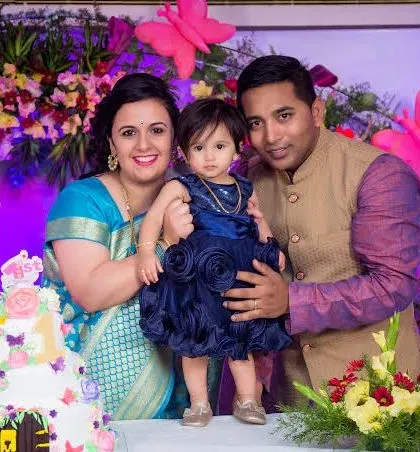 A family poses behind their daughter's first birthday cake. This classic shot is a must-have for any first birthday celebration.