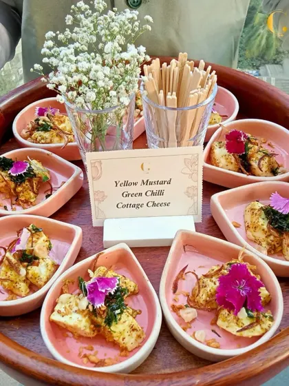 A tray of our Yellow Mustard Green Chilli Cottage Cheese appetizers, garnished with edible flowers. This dish is a perfect example of our ability to elevate traditional Indian flavours.