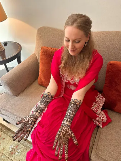 A beautiful bride admiring her classic and elegant full-arm mehndi.