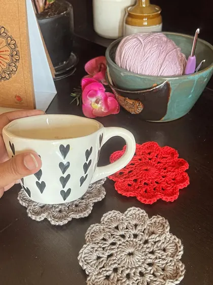 A hand holding a warm mug, perfectly complemented by a set of my custom-colored mandala coasters.