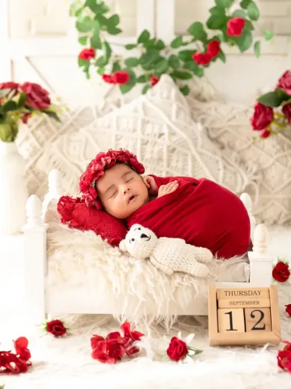 A side view of the red-themed setup, showing the baby in her tiny bed surrounded by roses.