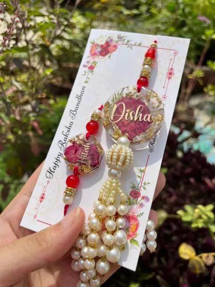An elegant resin rakhi and lumba set, featuring preserved rose petals, names, and beautiful pearl tassels.