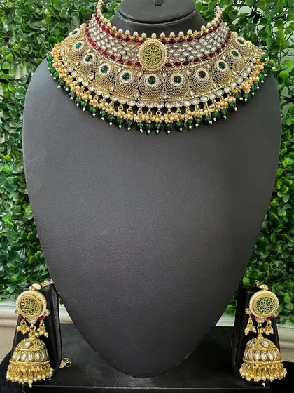 This rental choker set features intricate filigree work with green enamel and matching jhumkas. It's a great choice for a bride who appreciates detailed craftsmanship.