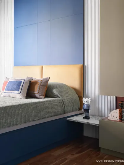 A shot of the kids' bed with its colorful cushions and a tall blue headboard, creating a fun and cozy sleeping area.