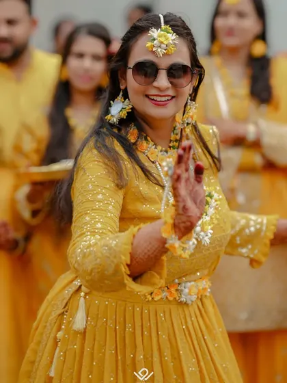 A bride dances with abandon at her Haldi ceremony, surrounded by friends and family in a sea of yellow.