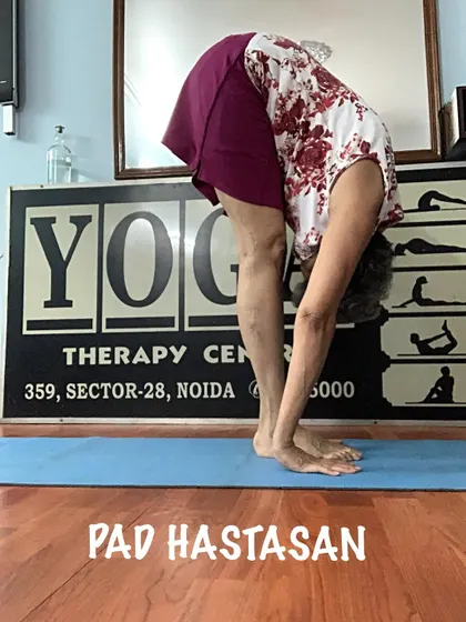 A demonstration of Padahastasana, a standing forward bend that stretches the back of the legs and improves posture.