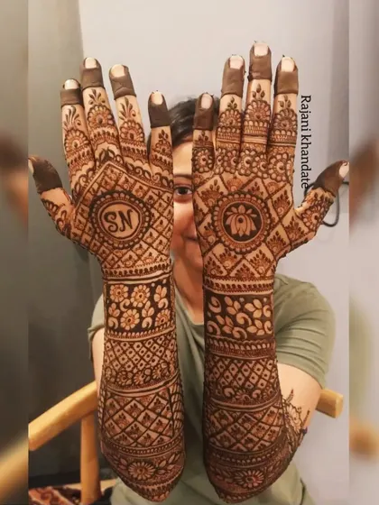 A full view of a personalized bridal design, featuring the couple's initials "SN" and a lotus motif. The design is a beautiful blend of personal elements and traditional geometric and floral patterns.