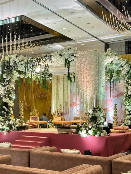 The completed mandap, a masterpiece of floral artistry. The archway of white flowers, combined with the soft pink stage and lotus backdrop, creates a serene and romantic atmosphere.