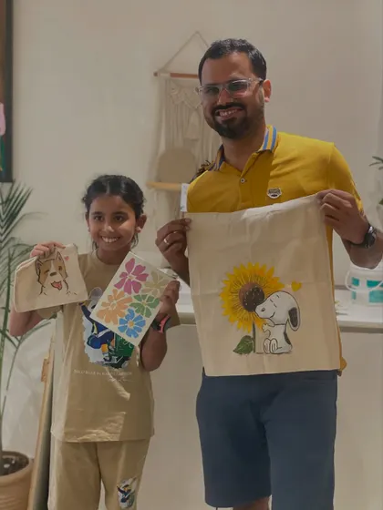 A father and daughter duo proudly present their finished tote bags. Creating functional art like this is a fun way to make something you can use every day.