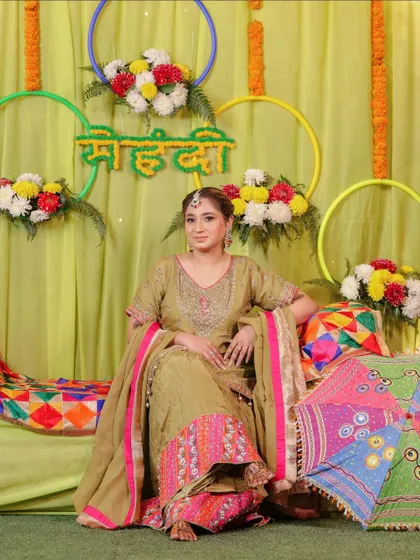 The bride posing against her colorful Mehndi backdrop, looking radiant and happy.