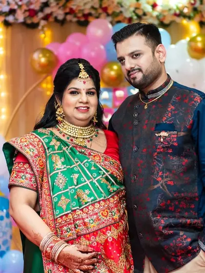 A formal portrait of the couple at their baby shower. Dressed in stunning traditional wear against a backdrop of festive balloons, they look radiant and ready to welcome their baby.