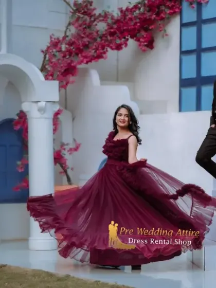 The woman twirls in a ruffled maroon gown while her partner looks on, dressed in a black suit. This showcases how the outfits work together to create a dynamic and interactive photo opportunity.