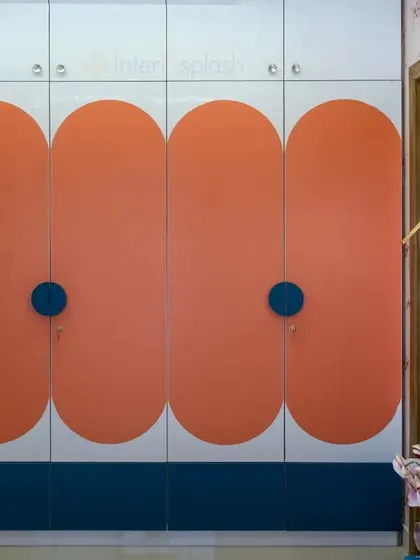 This custom wardrobe for a kid's room uses a playful color-block design with orange and blue. The round handles are easy for little hands to use.