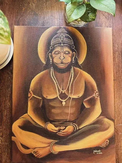 The Hanuman painting displayed on a wooden surface, surrounded by plants.