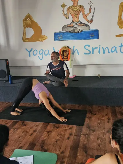 I guide a student through Downward-Facing Dog, demonstrating the pose from the front of the class.