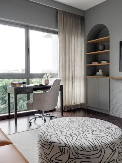 The family room in the Neutral Chic home includes a cozy study nook with an arched built-in bookshelf. The grey tones create a moody yet comfortable atmosphere.