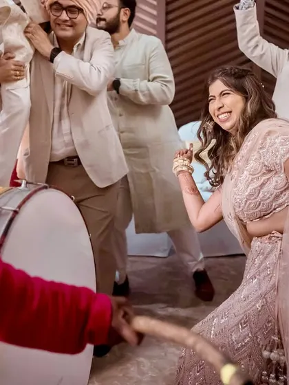 The bride joins the Baraat. This fun, energetic shot shows the bride dancing with the dhol player, a modern and exciting twist.