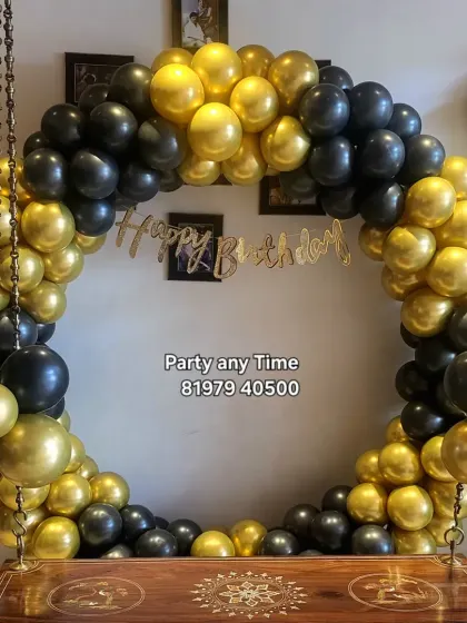 A simple but striking black and gold circular balloon arch built around a traditional Indian swing (jhoola).