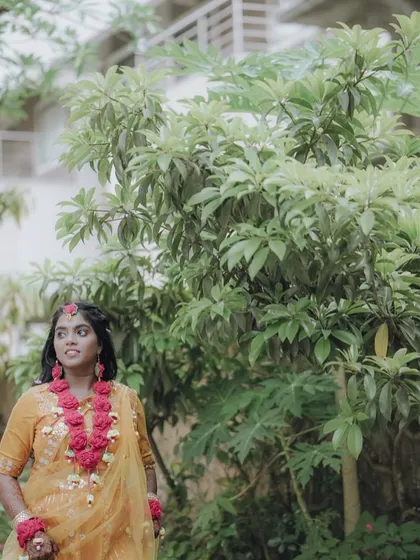 A candid shot of the bride looking up, surrounded by greenery at her Haldi event.