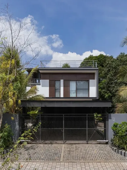 Exterior views of the Mango Tree Yard home, highlighting its contemporary form, clean lines, and the use of screens for privacy and ventilation.