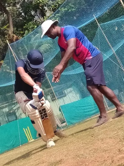 Here I am working with a batsman on his technique. Correcting small details in the stance and swing can make a huge difference in a player's game.