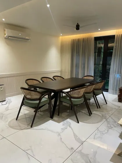 We gave this classic dining set a modern twist. The chairs feature traditional cane backing paired with a contemporary frame and soft green bouclé seats, set against a clean, white marble floor for a fresh and pleasant dining room design.