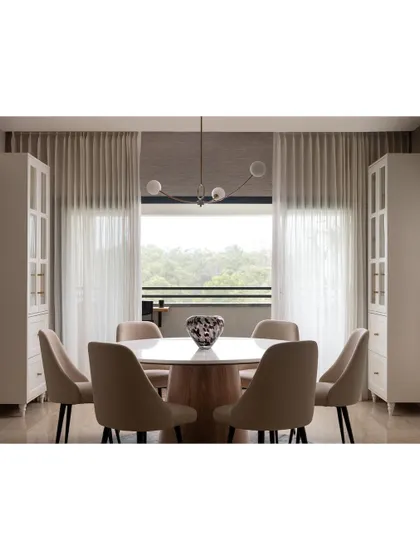 The dining room in the Warm Minimal home was designed to frame the gorgeous view of the forests. A round marble-topped table and upholstered chairs create an intimate and elegant setting.