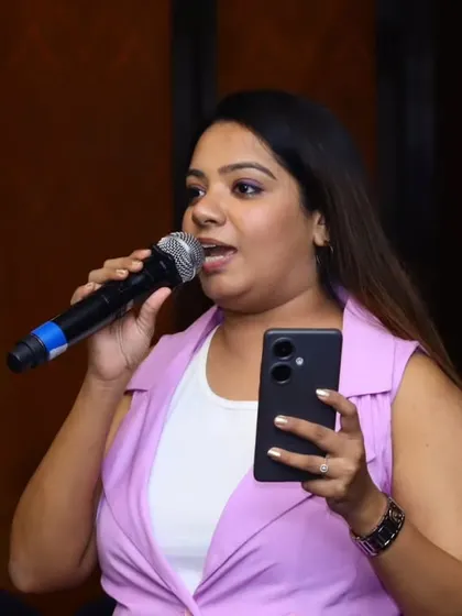 A close-up shot of me hosting the Infosys event. I often use my phone for interactive polls or to manage event cues, ensuring a seamless and modern hosting experience.