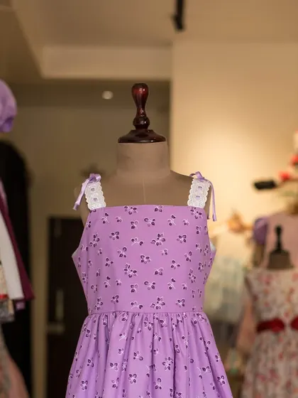 A simple and sweet lavender dress with a ditsy floral print. The lace-trimmed straps that tie at the shoulder add a delicate, adjustable detail.