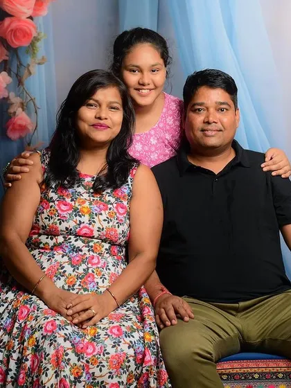 A classic family portrait with a mother, father, and daughter, set against a beautiful floral backdrop in the studio.