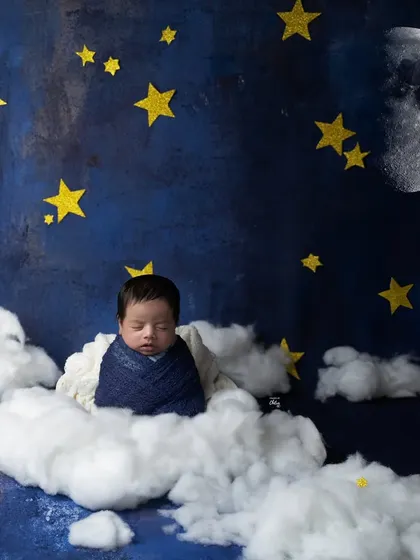 A wide shot of our "dreamland" theme, with a baby sleeping peacefully on a cloud under a starry night sky with a big, bright moon.
