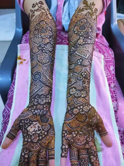 A stunningly detailed bridal mehndi, with the groom's name, Abdullah, written on the palm.