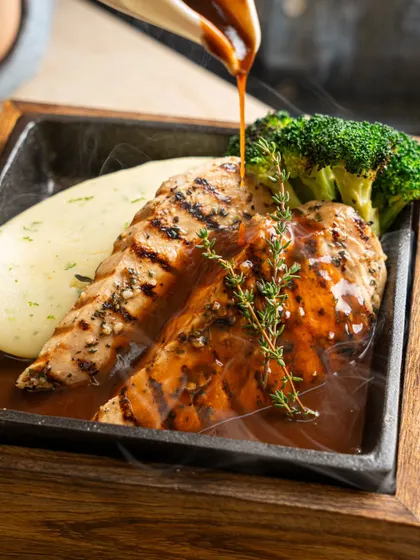 A sizzling steak platter with gravy being poured over it. We capture the steam and sizzle to create a multi-sensory experience for the viewer.