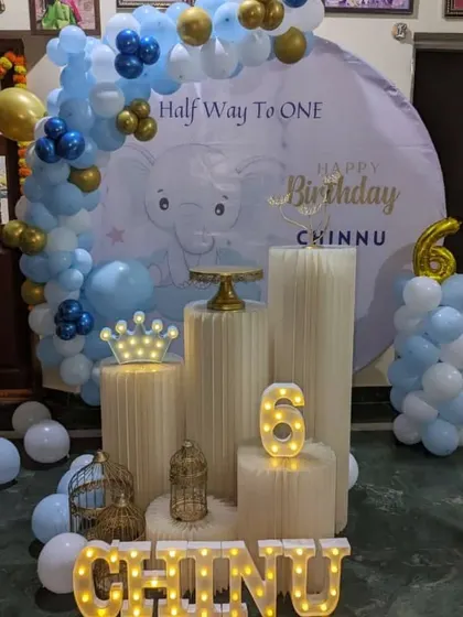 A "Half Way to One" celebration for a six-month-old. The blue and gold balloon decor is paired with a custom elephant-themed backdrop.