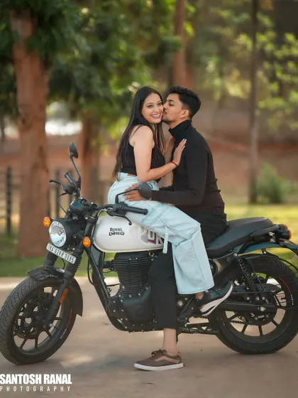A cool and casual pre-wedding photo featuring a couple on a Royal Enfield Hunter motorcycle. We love incorporating elements like bikes to reflect the couple's style and personality.