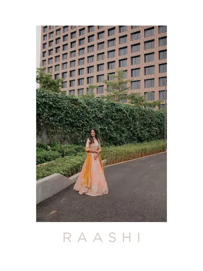 A stylish portrait of Raashi at her Haldi ceremony, set against a modern building. This shot contrasts traditional attire with contemporary architecture, creating a unique and fashionable image.