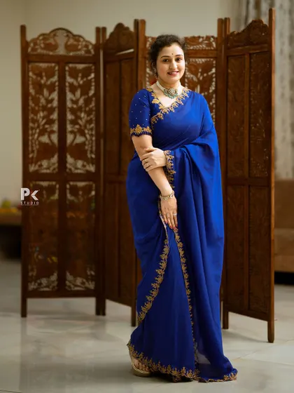 A royal blue saree with intricate gold embroidery on the borders, paired with a matching embroidered blouse.