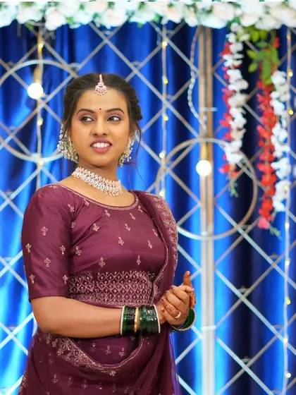 A candid shot showcasing the client's happiness and the decor details. The backdrop of blue drapes, lights, and floral arrangements adds to the celebratory feel of the event.