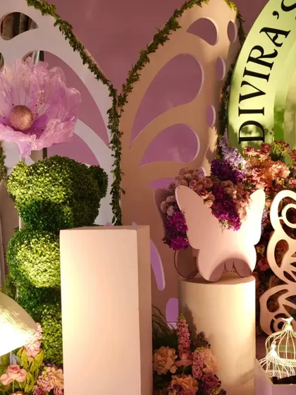 Detail shot of the luxury decor, featuring a topiary bear, large cutout butterfly wings, and oversized fabric flowers.