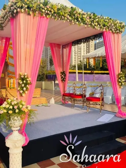An outdoor mandap setup at a temple, perfect for a traditional wedding ceremony. The pink draping and floral arrangements create a beautiful sacred space.
