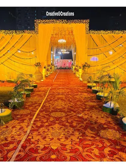 A wide shot of a grand yellow-themed entrance at night. The intricate draping and lighting create a magnificent facade for the event.