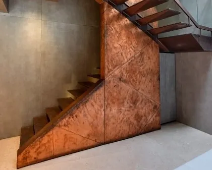 The patinated copper surface of the staircase catches the light, revealing beautiful textures and variations in color.