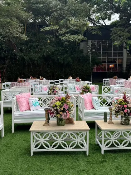 A wide view of the lawn party, with rows of white benches and tables creating a clean and elegant look.