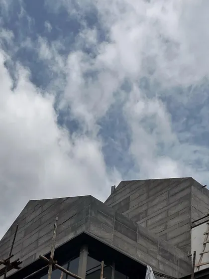 The strong geometry of a roofline under construction. Even in its unfinished state, the architectural form makes a statement against the cloudy sky.