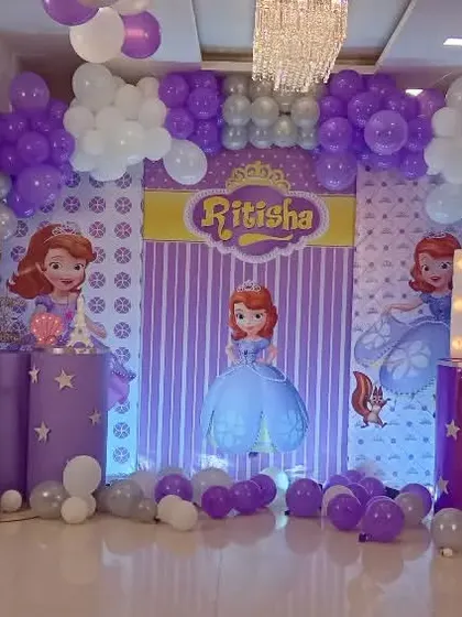 A 'Sofia the First' themed birthday party in her signature purple color. The decor includes multiple character cutouts, a custom backdrop, and extensive balloon work to create a magical castle feel.